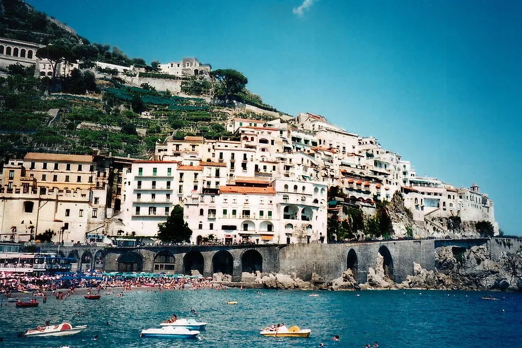 The colorful town of Amalfi climbing the cliffs above the harbor, with boats on the water